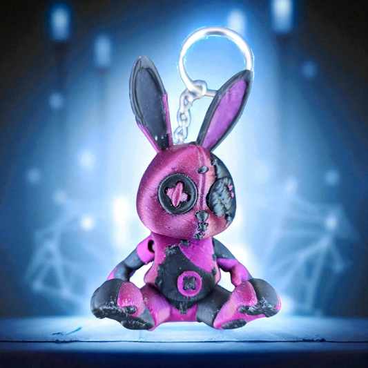 Pink rabbit-shaped keychain with black accents on a dark background