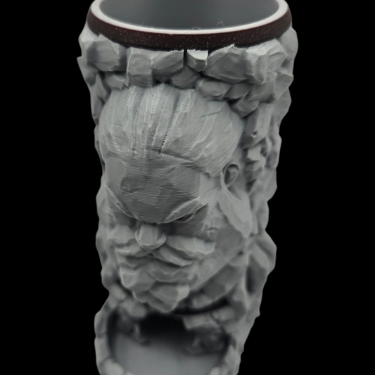 Ceramic mug with a decorative face design on a black background